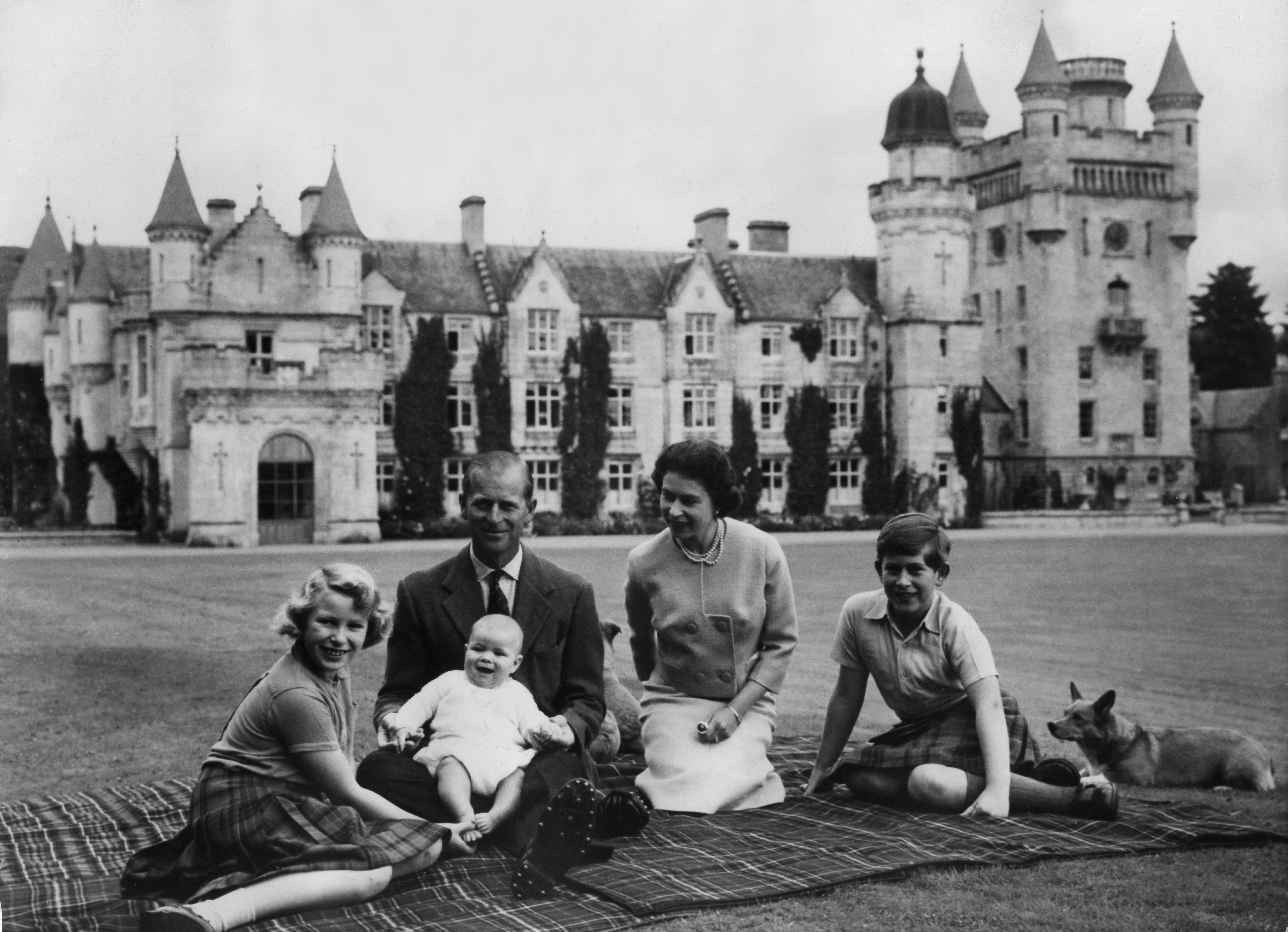 Королева Елизавета Вторая и принц Филипп, герцог Эдинбургский, со своими детьми принцем Эндрю (в центре), принцессой Анной (слева) и Чарльзом (справа) на пикнике возле замка Балморал. 8 сентября 1960.