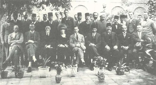 Фотография различных британских и иракских сановников в Багдаде в 1923 году в эпоху подмандатного Ирака. Со второго слева направо в первом ряду: Кинахан Корнуоллис, Сассун-эфенди Эскелл, Гертруда Белл. За Гертрудой Белл стоит Бернар Анри Бурдильон